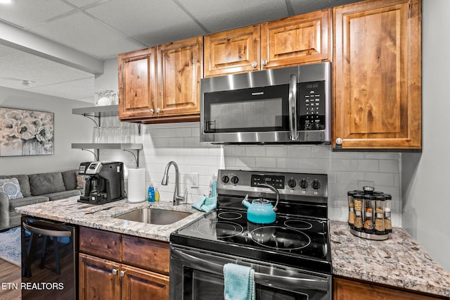 kitchen featuring a sink, stainless steel microwave, light stone counters, range with electric stovetop, and dishwasher