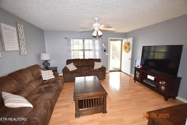 living area with a textured ceiling, light wood-style floors, baseboards, and ceiling fan