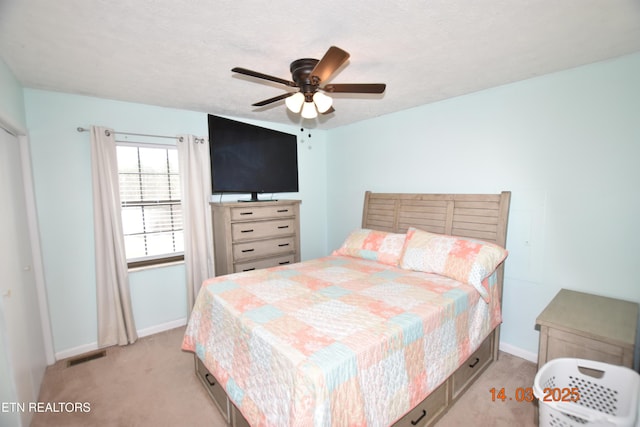 bedroom with ceiling fan, light colored carpet, visible vents, and baseboards