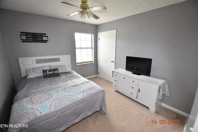 bedroom featuring light colored carpet, baseboards, a textured ceiling, and ceiling fan