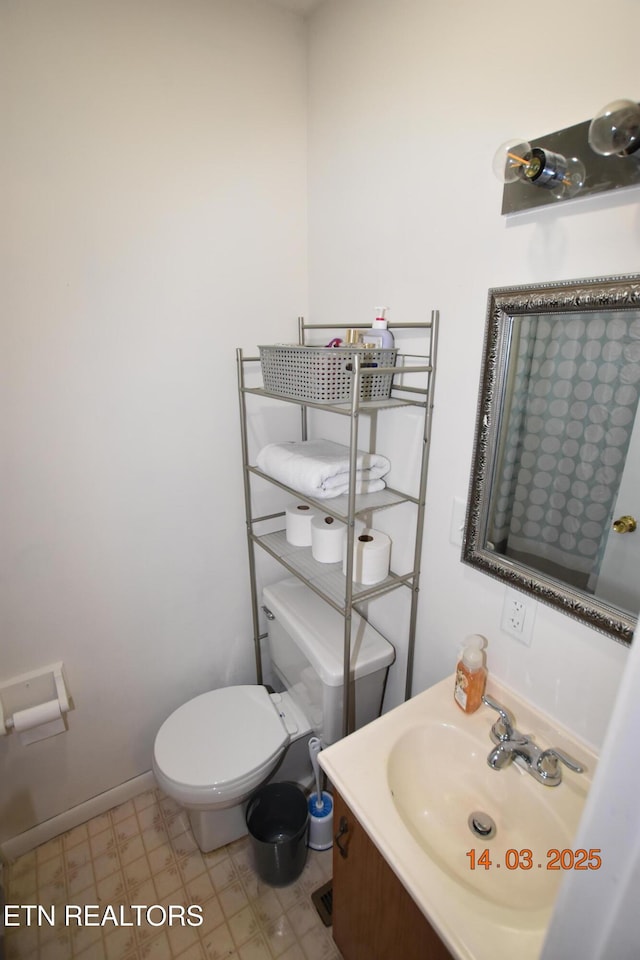 bathroom with toilet, vanity, and baseboards