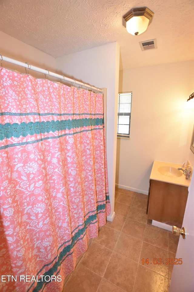 full bathroom with visible vents, a textured ceiling, tile patterned flooring, baseboards, and vanity