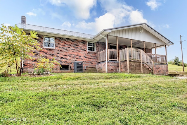 back of house featuring a yard, brick siding, covered porch, and metal roof