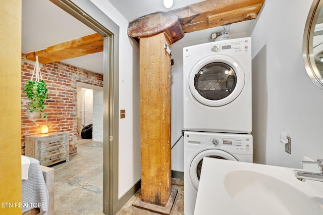 washroom with laundry area, brick wall, stacked washing maching and dryer, and a sink