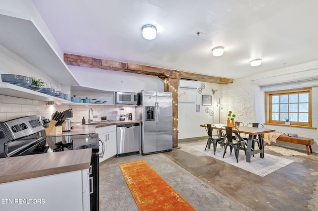 kitchen with butcher block countertops, a sink, a wall unit AC, stainless steel appliances, and decorative backsplash