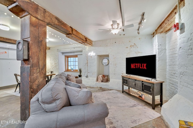 living area featuring beam ceiling, rail lighting, a ceiling fan, and concrete flooring