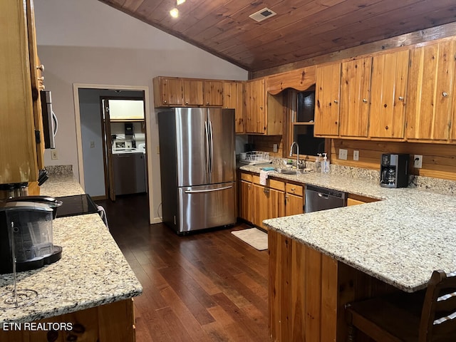 kitchen featuring dark wood-type flooring, a sink, appliances with stainless steel finishes, a peninsula, and vaulted ceiling