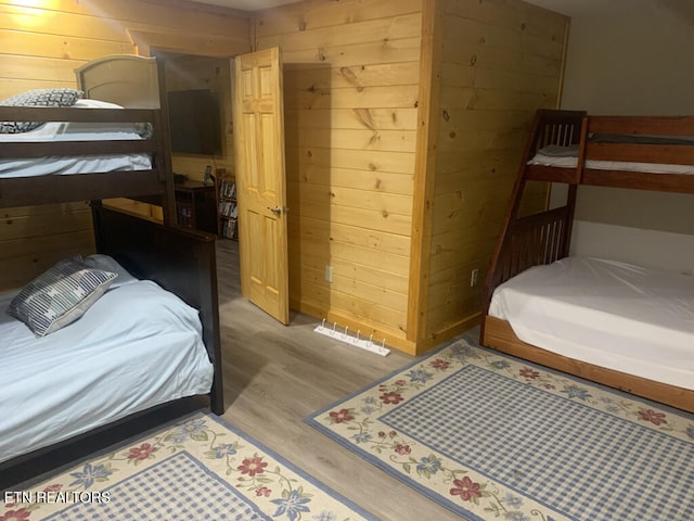 bedroom with wood finished floors and wood walls