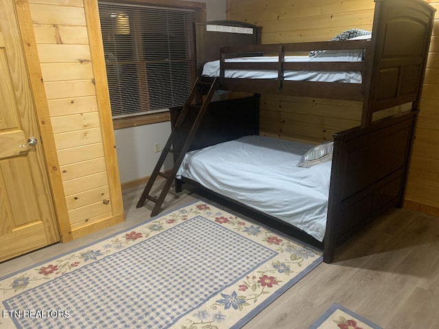 bedroom featuring light wood-type flooring and wooden walls