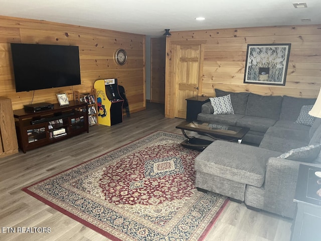 living room with recessed lighting, wood walls, and wood finished floors