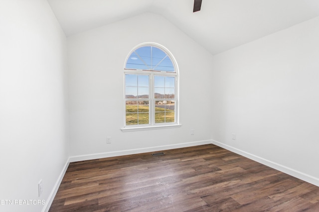 empty room featuring visible vents, a ceiling fan, dark wood finished floors, baseboards, and vaulted ceiling