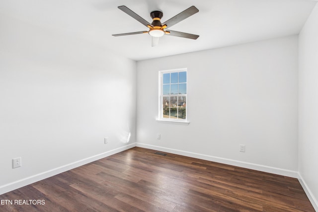 empty room with visible vents, dark wood-style floors, a ceiling fan, and baseboards