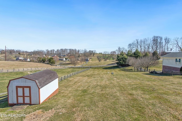 view of yard with a rural view, an outdoor structure, a shed, and fence