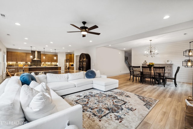 living room featuring recessed lighting, ceiling fan with notable chandelier, visible vents, and light wood finished floors