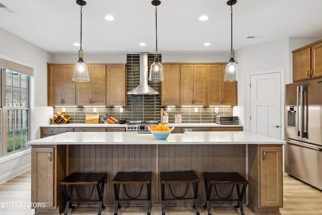 kitchen with a wealth of natural light, wall chimney exhaust hood, visible vents, and appliances with stainless steel finishes