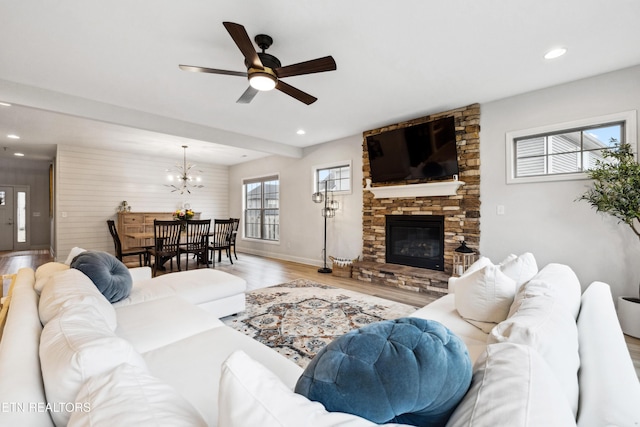 living area featuring baseboards, recessed lighting, ceiling fan with notable chandelier, a fireplace, and wood finished floors