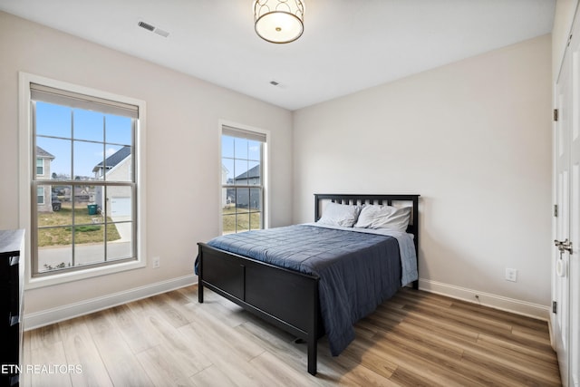 bedroom with visible vents, baseboards, and wood finished floors