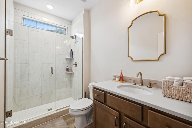 bathroom with a shower stall, toilet, and vanity