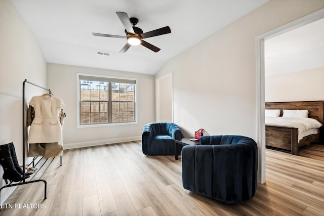 sitting room featuring visible vents, wood finished floors, baseboards, ceiling fan, and vaulted ceiling