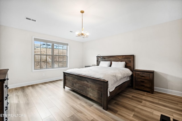 bedroom featuring an inviting chandelier, light wood-style flooring, and baseboards