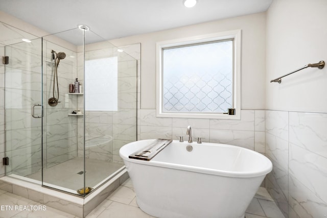 full bath featuring a marble finish shower, tile walls, a soaking tub, and marble finish floor