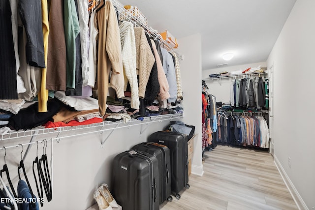 walk in closet with light wood finished floors