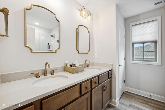 bathroom featuring double vanity, visible vents, wood finished floors, and a sink