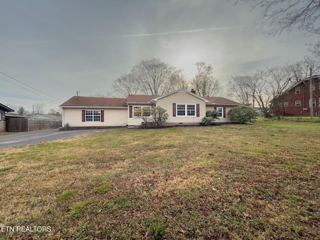 view of front facade with a front yard, fence, and aphalt driveway