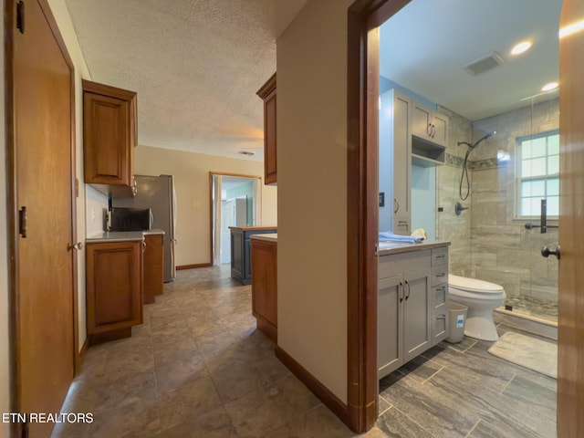 full bath featuring vanity, visible vents, a stall shower, and baseboards