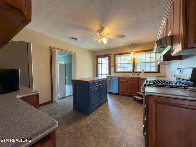 kitchen with under cabinet range hood, a sink, a kitchen island, appliances with stainless steel finishes, and ceiling fan