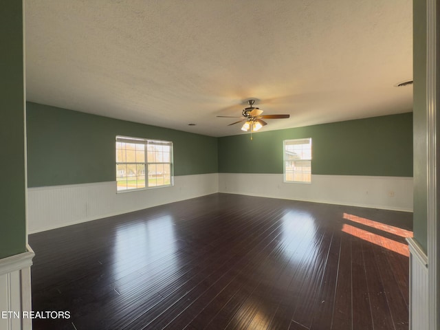 unfurnished room featuring a wainscoted wall, a textured ceiling, a ceiling fan, and wood-type flooring