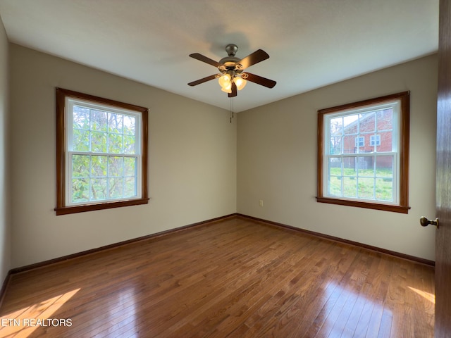 empty room with baseboards, wood-type flooring, a healthy amount of sunlight, and a ceiling fan