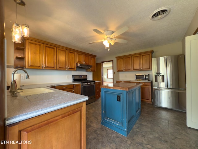 kitchen featuring brown cabinetry, visible vents, a sink, stainless steel appliances, and under cabinet range hood