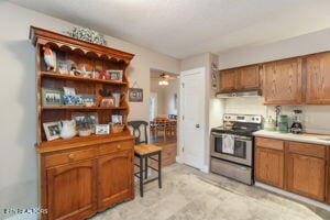 8836 Nubbin Ridge Rd, Knoxville, TN 37923 - kitchen featuring brown cabinets, light countertops, stainless steel range with electric cooktop, and extractor fan