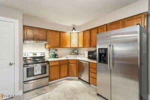8836 Nubbin Ridge Rd, Knoxville, TN 37923 - kitchen with brown cabinetry, under cabinet range hood, light countertops, and stainless steel appliances