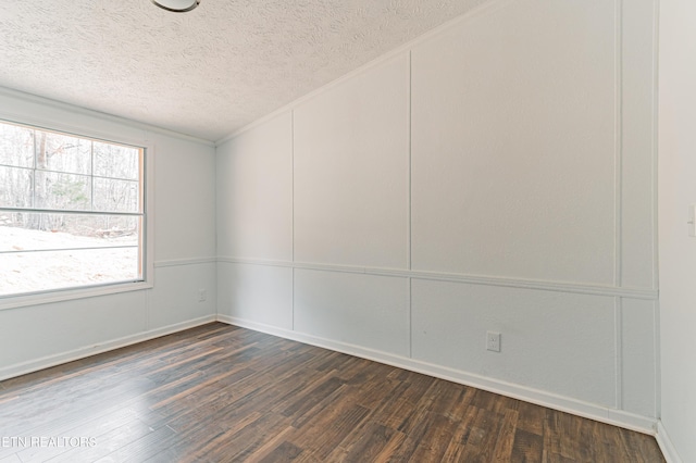 empty room featuring dark wood-style floors, a decorative wall, and a textured ceiling