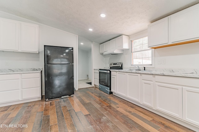 kitchen featuring white cabinets, stainless steel range with electric stovetop, freestanding refrigerator, and hardwood / wood-style floors