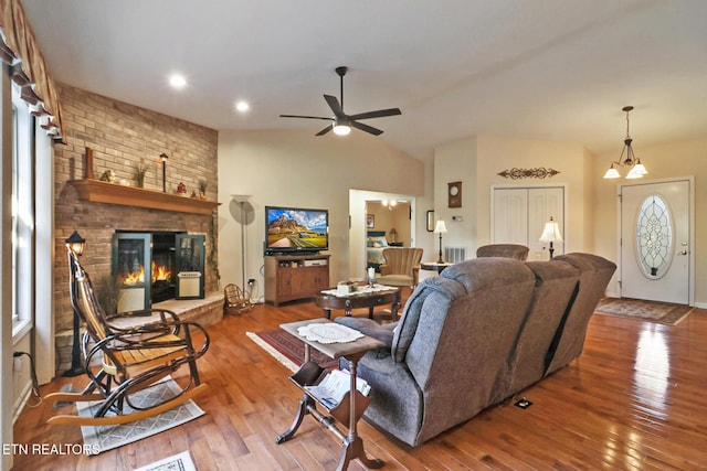 living area with a brick fireplace, ceiling fan, vaulted ceiling, and hardwood / wood-style flooring