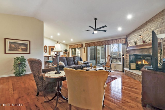 living room featuring lofted ceiling, a ceiling fan, wood finished floors, a fireplace, and baseboards