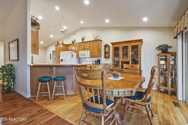 dining space with light wood finished floors, visible vents, ceiling fan, and lofted ceiling