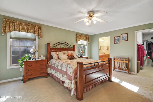 bedroom featuring light carpet, ensuite bathroom, crown molding, baseboards, and a spacious closet