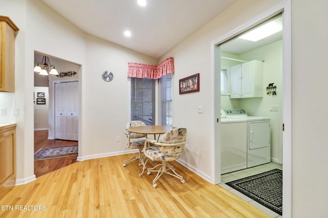 dining room featuring light wood-type flooring, washing machine and dryer, baseboards, a chandelier, and vaulted ceiling