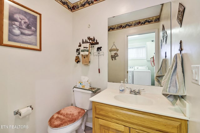 bathroom featuring washing machine and clothes dryer, toilet, and vanity