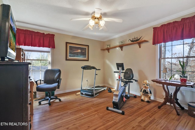 workout room with light wood-style flooring, baseboards, crown molding, and a ceiling fan