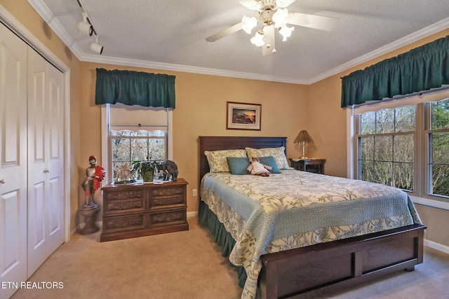 carpeted bedroom with crown molding, rail lighting, a closet, a textured ceiling, and a ceiling fan