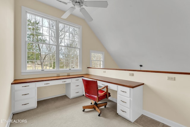 home office featuring baseboards, ceiling fan, lofted ceiling, light carpet, and built in study area