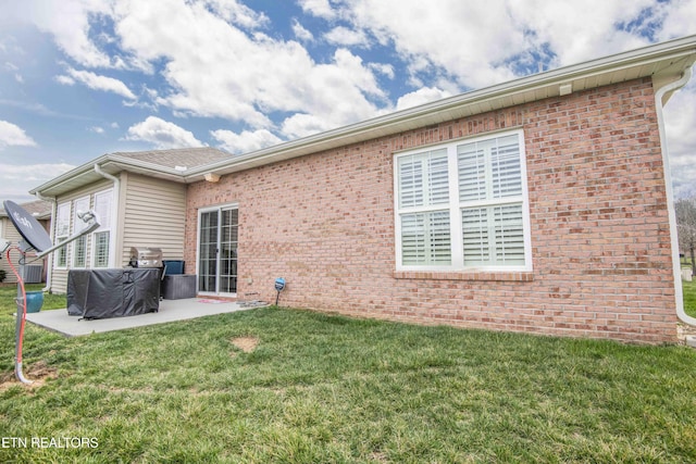 back of house with a patio area, brick siding, and a yard