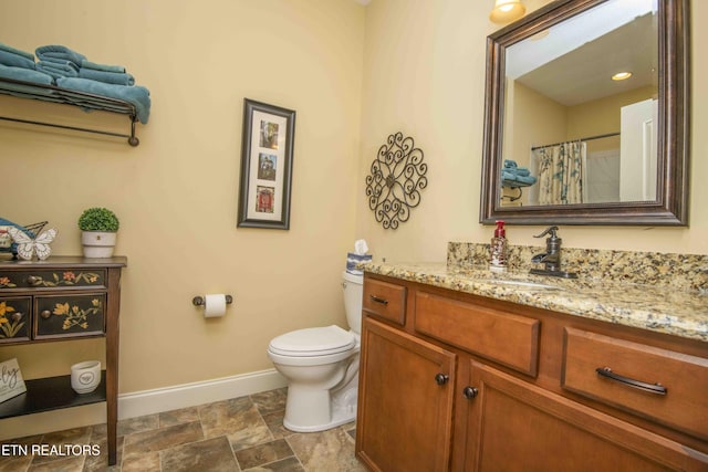 bathroom featuring baseboards, toilet, a shower with shower curtain, stone finish floor, and vanity