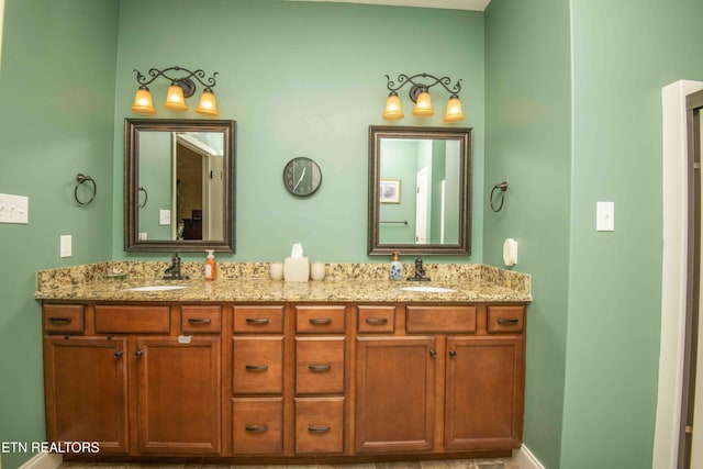 bathroom with double vanity, baseboards, and a sink