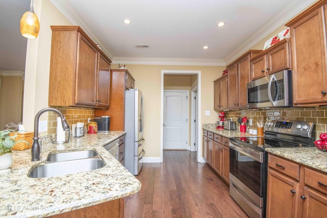 kitchen featuring light stone counters, stainless steel appliances, crown molding, and a sink